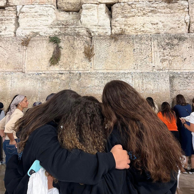 Three girls hugging looking at the Kotel/Western wall in Jerusalem.